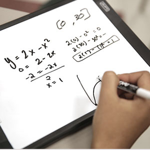 A hand writing equations on a whiteboard